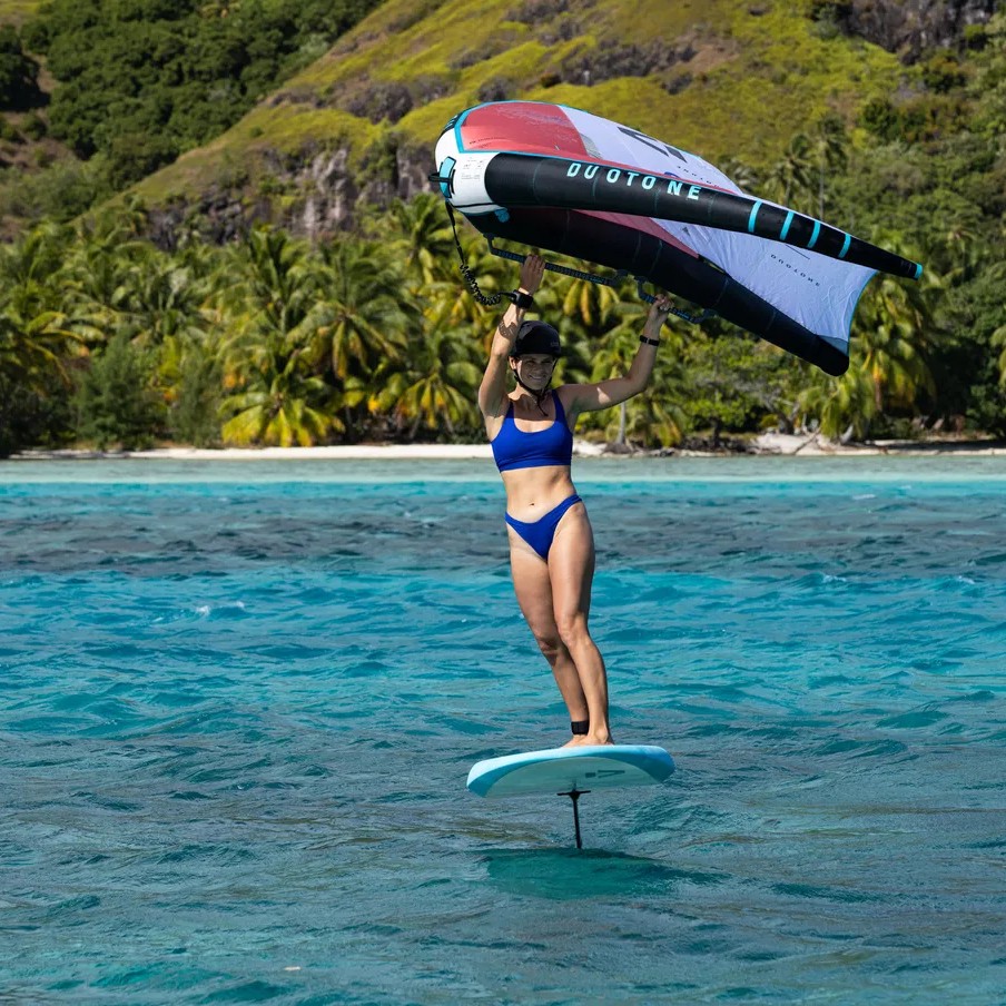 Rider en wingfoil sur la planche Duotone Sky Start 2024 dans un lagon tropical, en train de voler au-dessus de l’eau avec une aile Duotone, idéale pour débuter en wing.