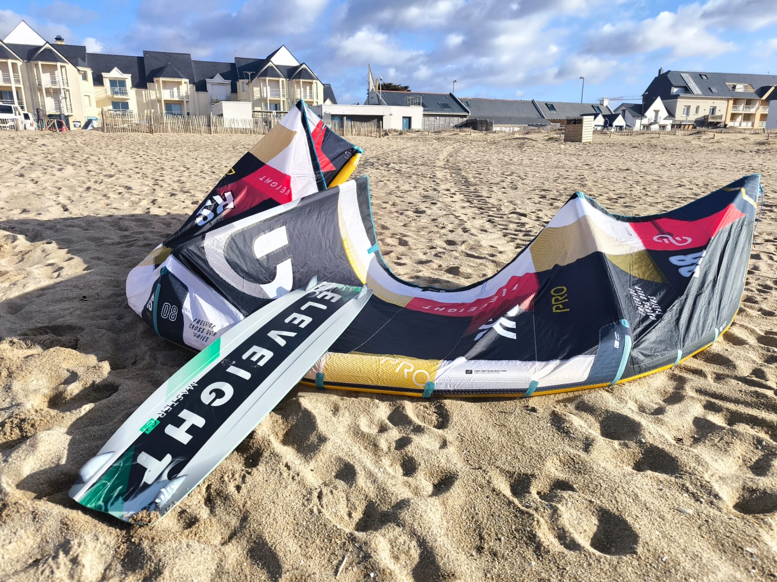 Aile de kitesurf Eleveight RS PRO V1 2025 posée sur le sable, avec des appartements en arrière-plan – aile performante pour freeride et big air.