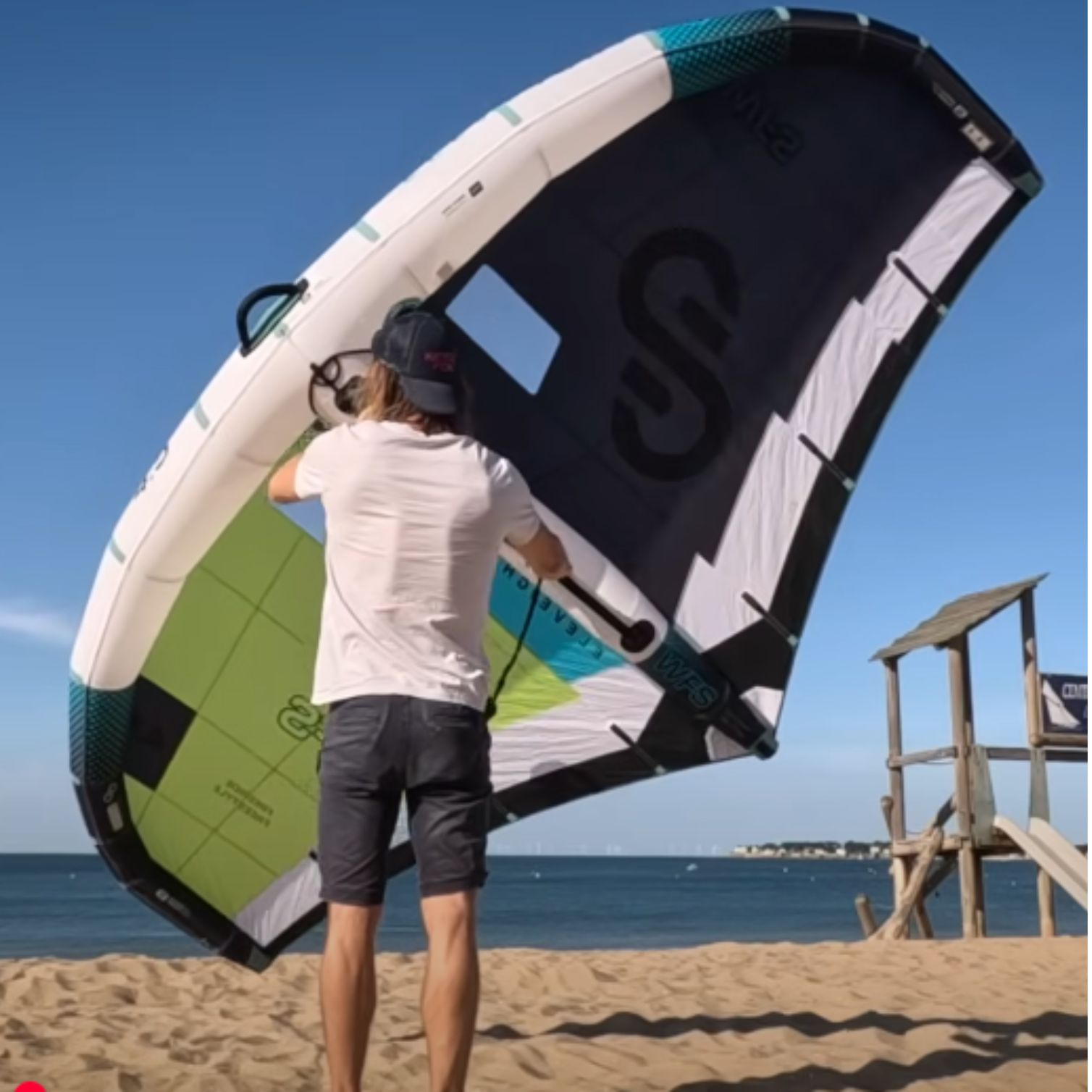Aile ELEVEIGHT WFS V6 sur la plage, en train d’être tenue par un rider.