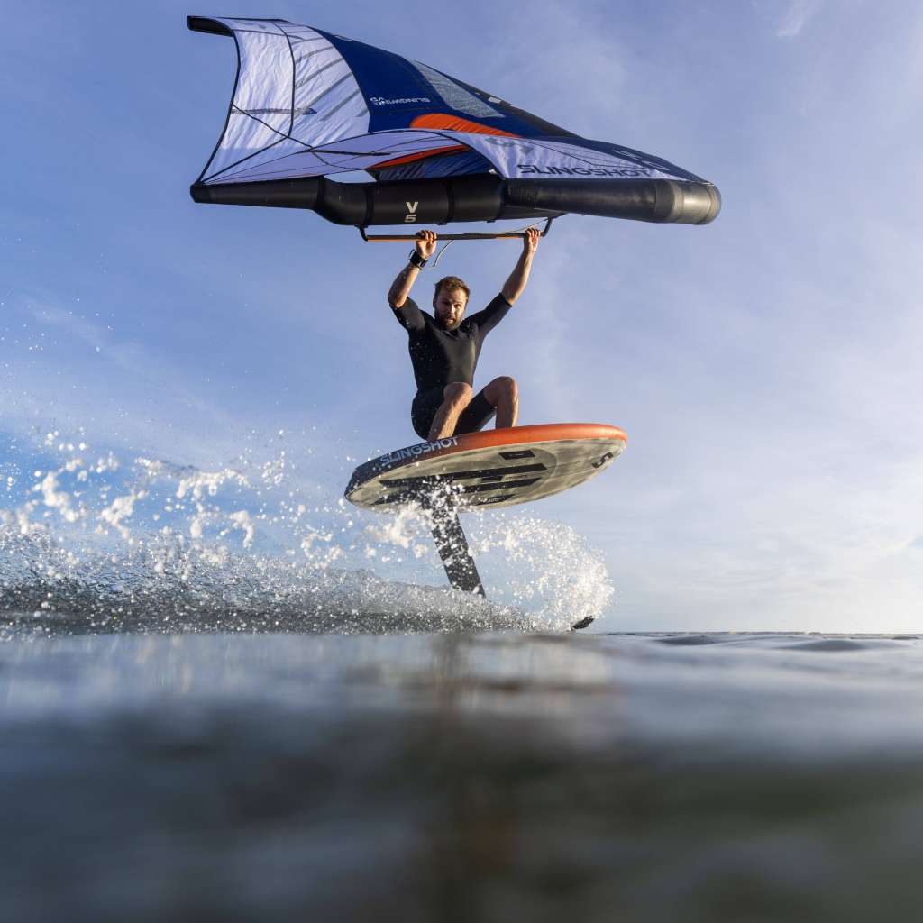 Surfeur en surfoil avec foil Slingshot One Lock, glisse sur une vague en short